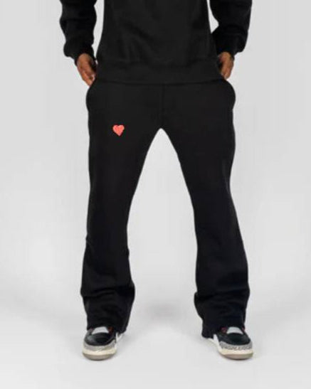 Person wearing a black hoodie and pants with heart designs on a white background