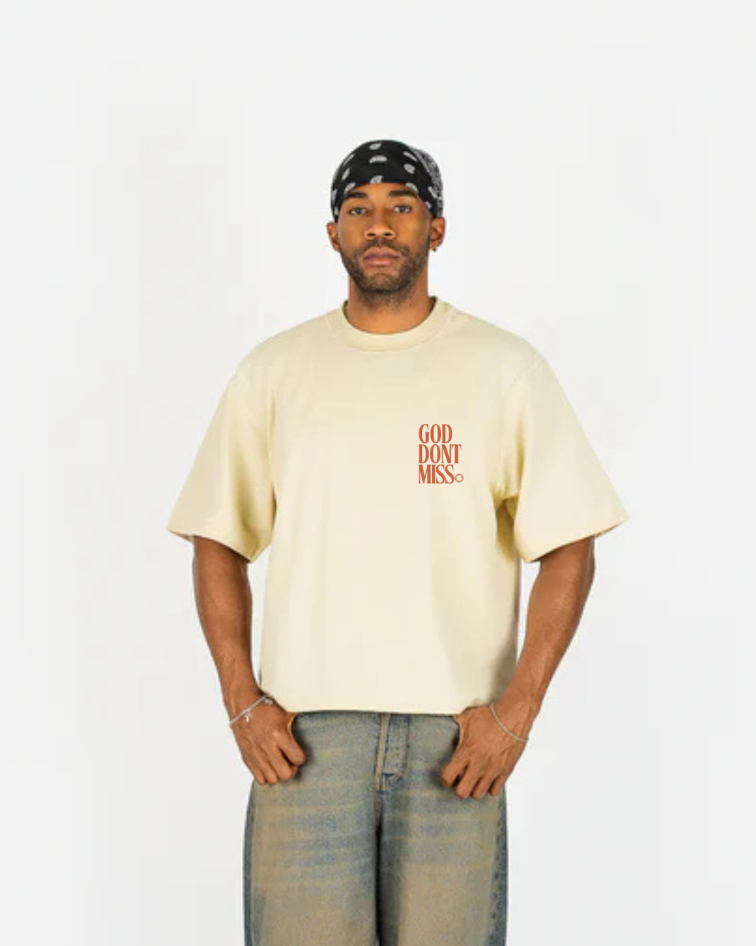 Man wearing a beige t-shirt with text and a bandana on a white background