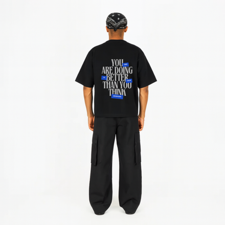 Person wearing a black t-shirt with motivational text on a white background